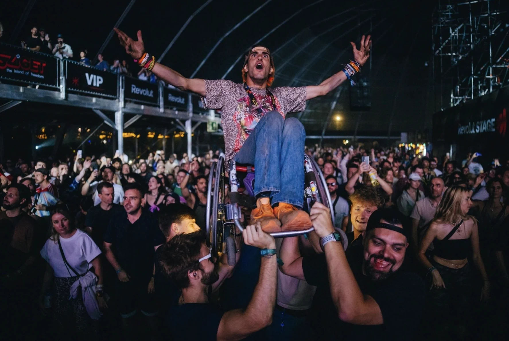 Festivalgoers lifting a wheelchair user above the crowd at Sziget