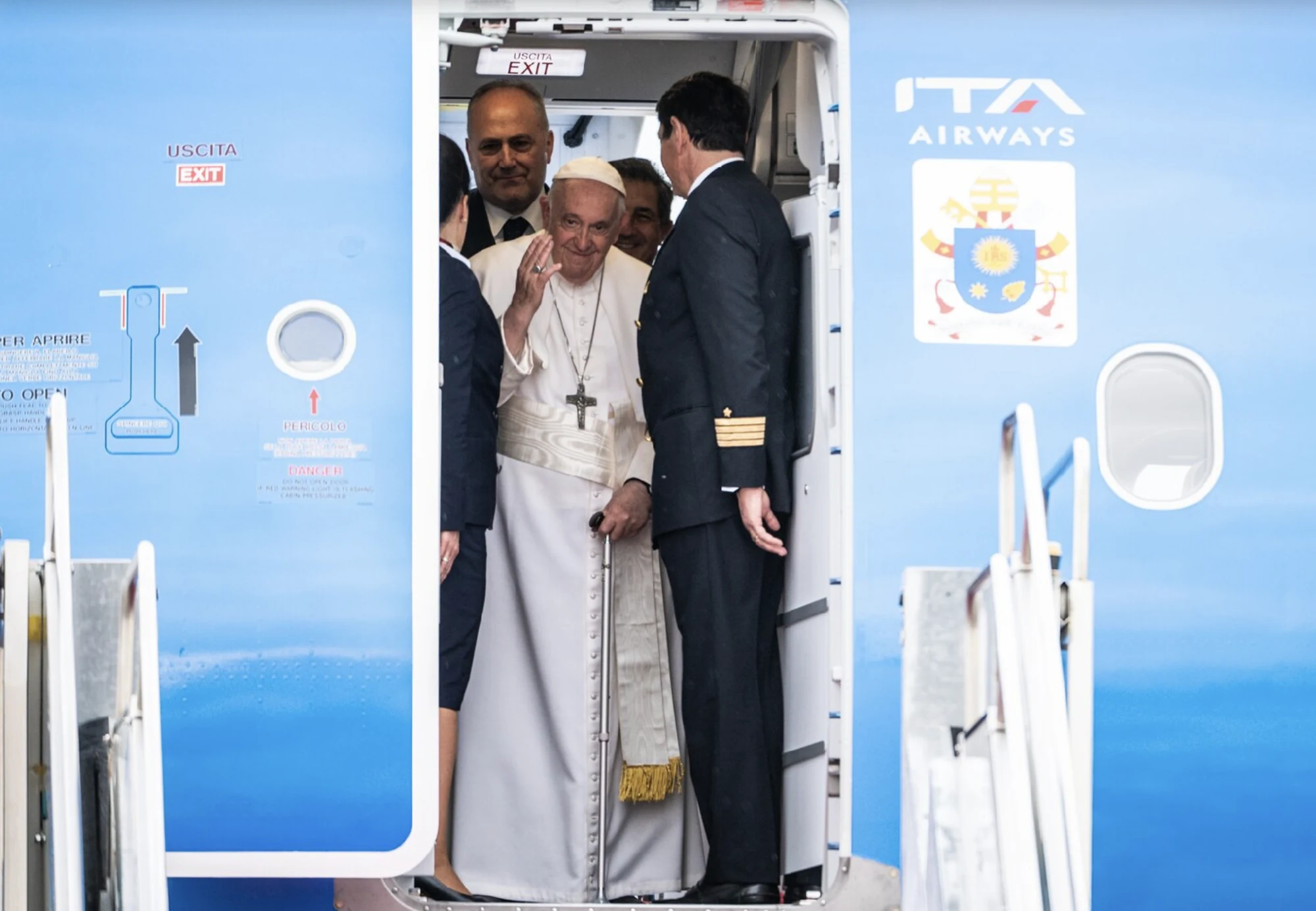 Pope Francis waving from the doorway of an aircraft
